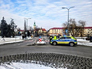 Kolorowe zdjęcie oznakowanych radiowozów Policji oraz umundurowanych policjantów na tle osób biorących udział w orszaku.