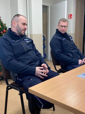 Kolorowe zdjęcie umundurowanych funkcjonariuszy policji siedzących przy stole.
