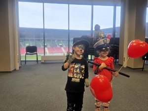 Kolorowe zdjęcie dzieci trzymające w ręku kajdanki i pałkę służbową Policji.