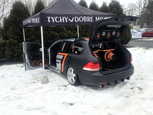 Kolorowe zdjęcie samochodu z otwartym bagażnikiem w którym znajduje się nagłośnienie imprezy.