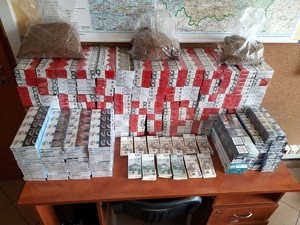 Kolorowe zdjęcie stołu na którym znajdują się paczki papierosów oraz duża suma pieniędzy w nominałach 100 i 200 złotowych.