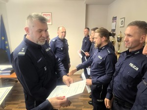 Kolorowe zdjęcie komendanta tyskiej jednostki wręczającego dyplom policjantowi.