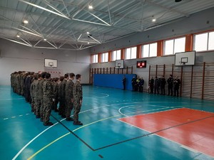 Kolorowe zdjęcie uczniów klas mundurowych podczas zbiórki na sali gimnastycznej.