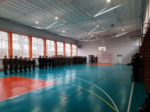 Kolorowe zdjęcie uczniów klas mundurowych podczas zbiórki na sali gimnastycznej.