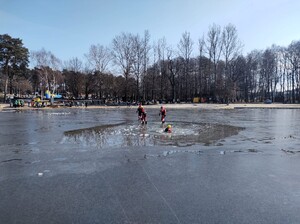 Kolorowe zdjęcie ratowników Wodnego Ochotniczego Pogotowia Ratowniczego stojących na tafli jeziora, jeden z nich znajduje się w wodzie.