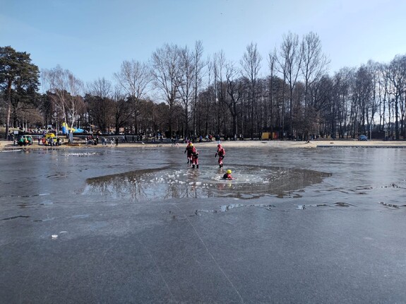 Kolorowe zdjęcie ratowników Wodnego Ochotniczego Pogotowia Ratowniczego stojących na tafli jeziora, jeden z nich znajduje się w wodzie.