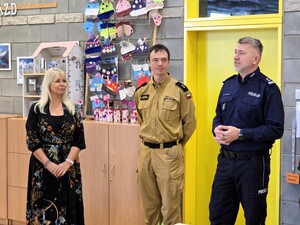 Kolorowe zdjęcie Komendanta Miejskiego Policji w Tychach podczas przemówienia, stojącego w towarzystwie Dyrektor Szkoły numer 24 w Tychach oraz funkcjonariusza Państwowej Straży Pożarnej.