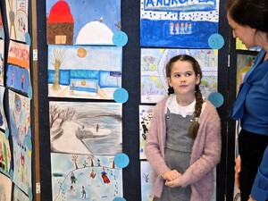 Kolorowe zdjęcie dziewczynki na tle prac plastycznych.