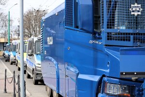 Kolorowe zdjęcie stojących w kolumnie oznakowanych pojazdów Policji.