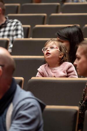 Dziewczynka z wyrazem zachwytu na twarzy siedząca na widowni.