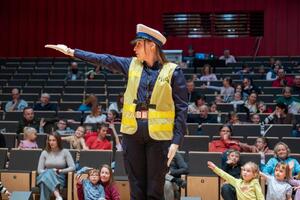 Umundurowana policjantka symulująca na scenie kierowanie ruchem.