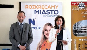 Kobieta i mężczyzna przemawiający do uczestników turnieju.