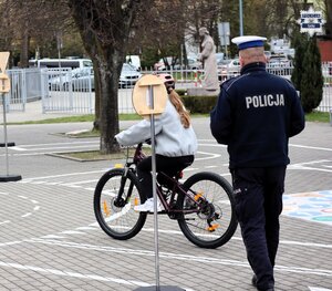 Umundurowani policjanci podczas egzaminowania młodzieży na rowerowym placu manewrowym.