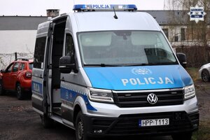 Oznakowany radiowóz Policji typu bus stojący przy drodze.