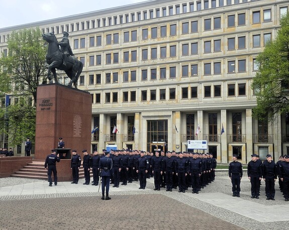 Nowo przyjęci policjanci stojący na baczność przy pomniku Józefa Piłsudskiego.