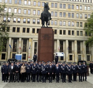 Goście honorowi oraz umundurowani oficerowie Policji stojący na tle pomnika Józefa Piłsudskiego.