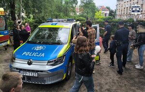 Umundurowani policjanci przy oznakowanym radiowozie podczas prezentacji dla uczestników wydarzenia.