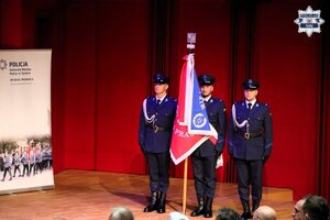 Umundurowani policjanci pocztu sztandarowego stojący na scenie.