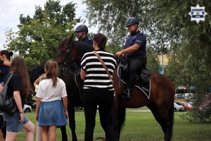 Rodzice z dziećmi stojący w pobliżu koni służbowe policji.