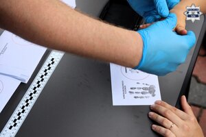 Technik kryminalistyki podczas pokazu pobierania odcisków linii papilarnych.