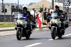 Policjanci jadący ulicą oznakowanymi motocyklami.