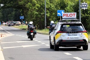 Pojazd pilota wyścigu, w tle jadące przed nim motocykle policyjne.