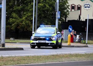 Oznakowany radiowóz Policji zabezpieczający skrzyżowanie.