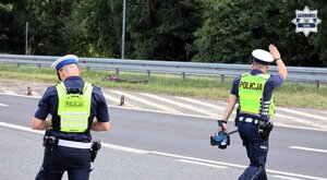 Umundurowani policjanci Wydziału Ruchu Drogowego wychodzą na jezdnię.