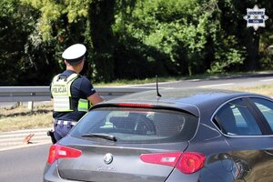 Umundurowany Policjant Wydziału Ruch Drogowego podczas kontroli kierującego pojazdem.