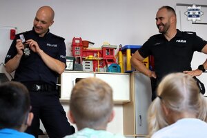 Umundurowani policjanci rozmawiają z grupą przedszkolaków.