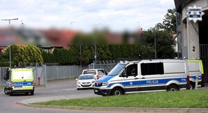 Oznakowane radiowozy policyjne stojące na parkingu. W tle widoczny stadion miejski.